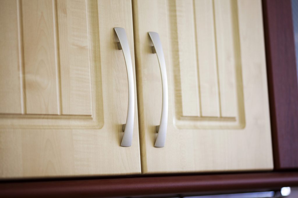 Close view of cream kitchen cabinet doors with brushed steel bar handles
