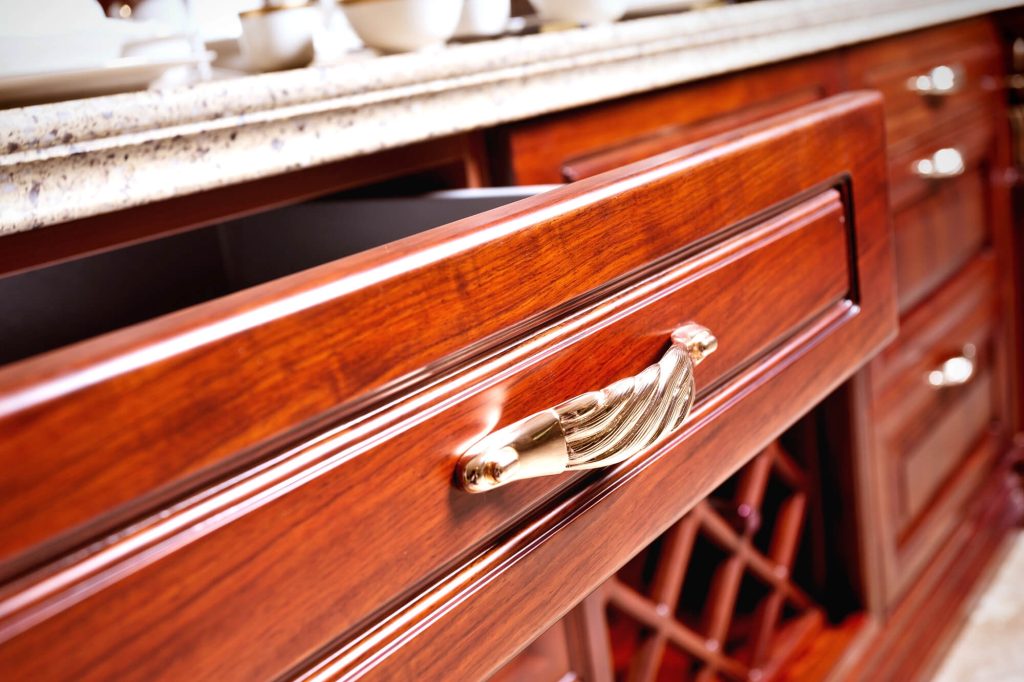Open drawer in dark timber cabinetry with cutlery in a fitted insert