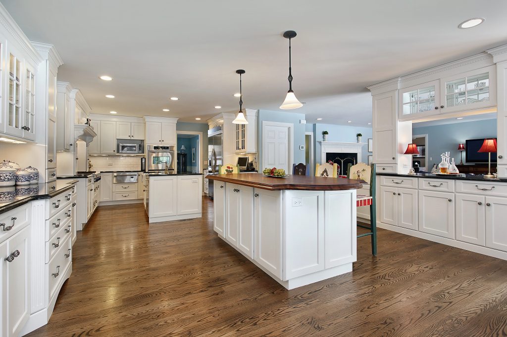 White kitchen with a large timber topped island and pendant lights above it
