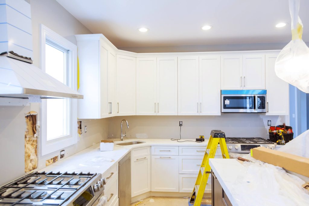 Installer fitting white shaker cabinets in a bright kitchen