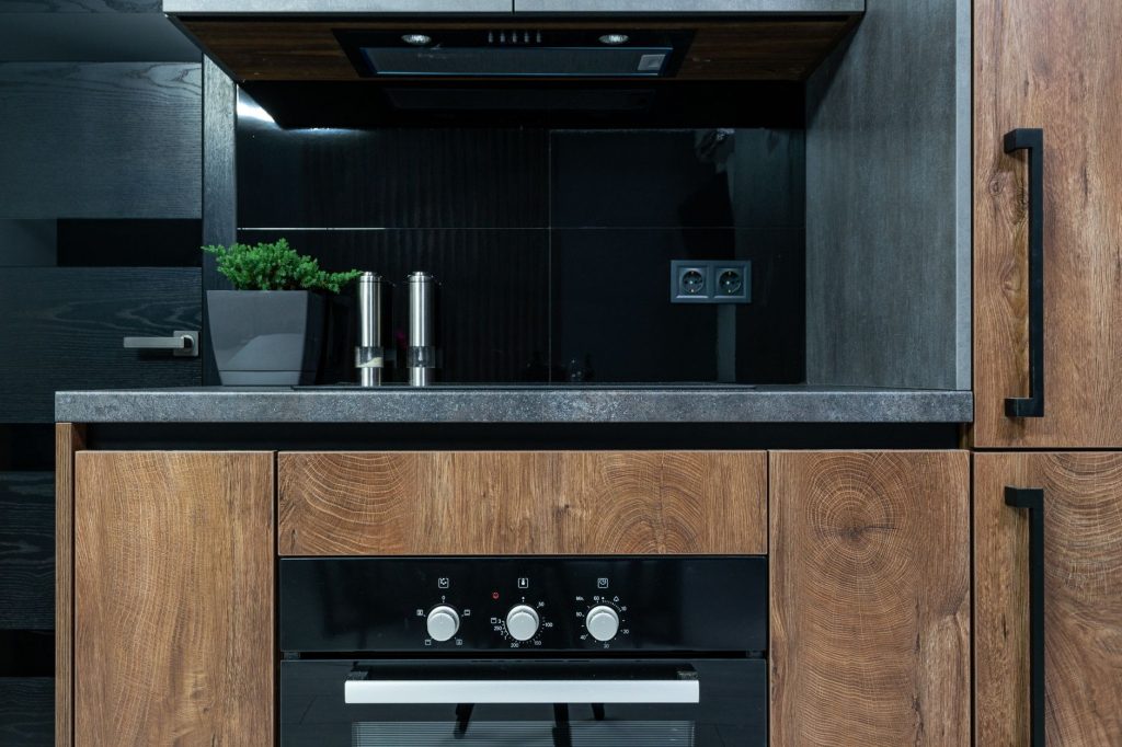 Modern kitchen with dark wood cabinetry, black units and a stone backsplash