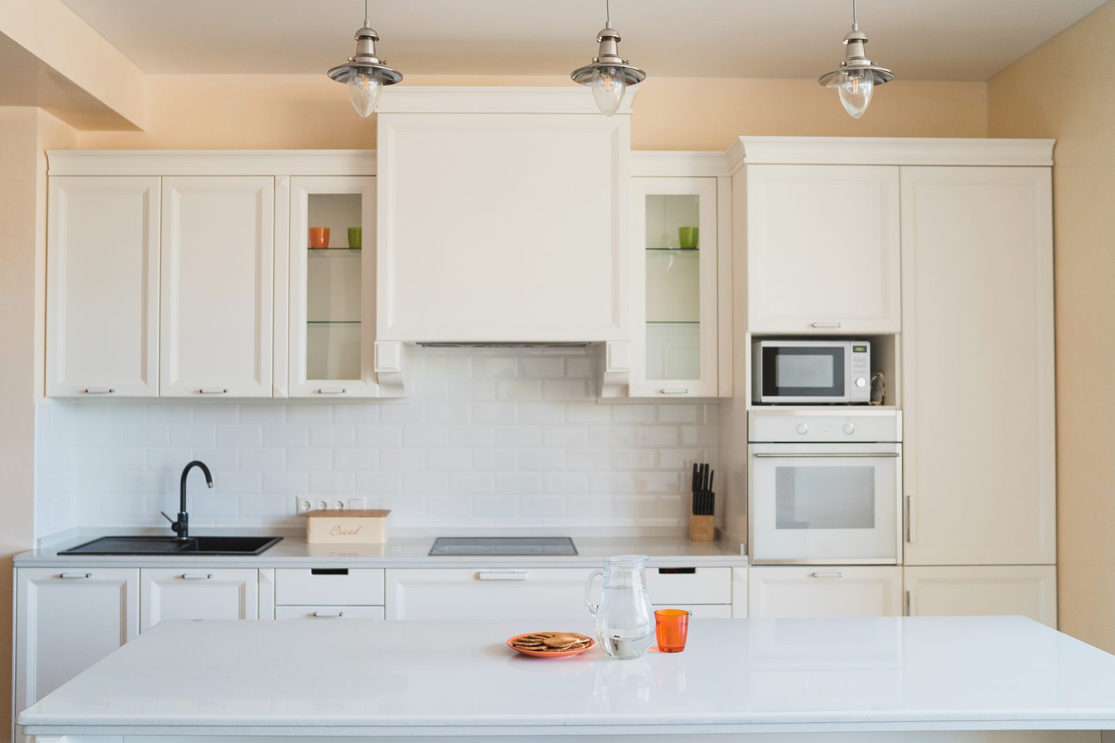 Cream shaker kitchen with a long island, glass fronted upper cabinets and pendant lights