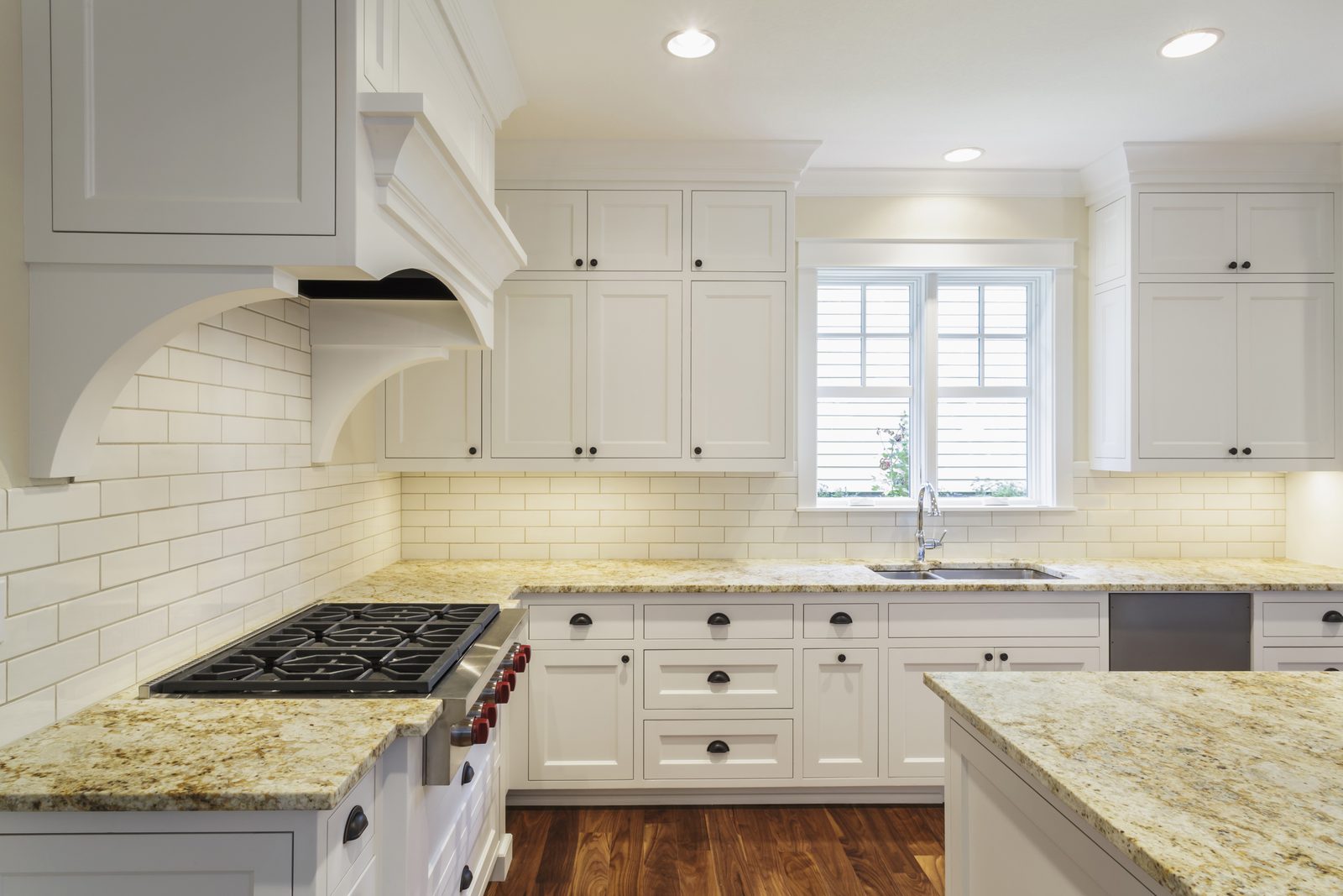 Traditional kitchen with granite counters, cream cabinets and an arched range hood