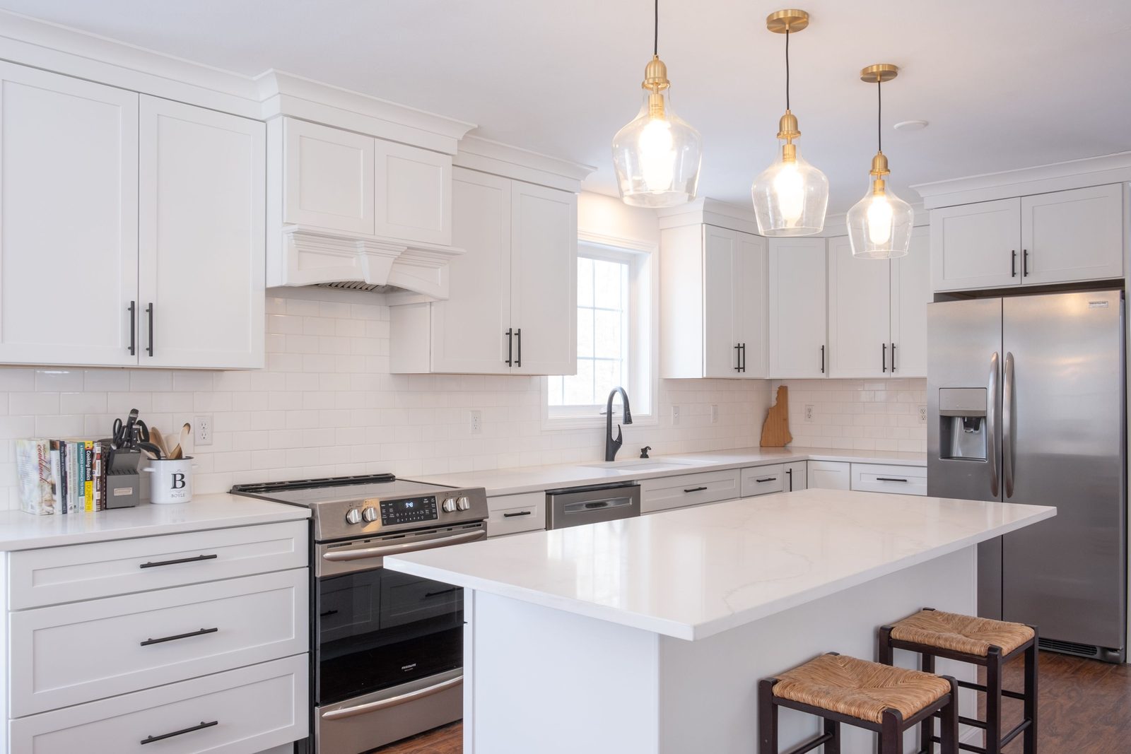 White shaker kitchen with an island, timber bar stools and brass pendant lights