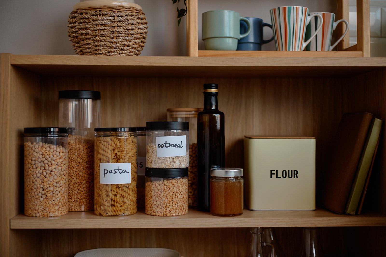 Timber pantry shelf with labeled glass jars of pasta, oatmeal and flour