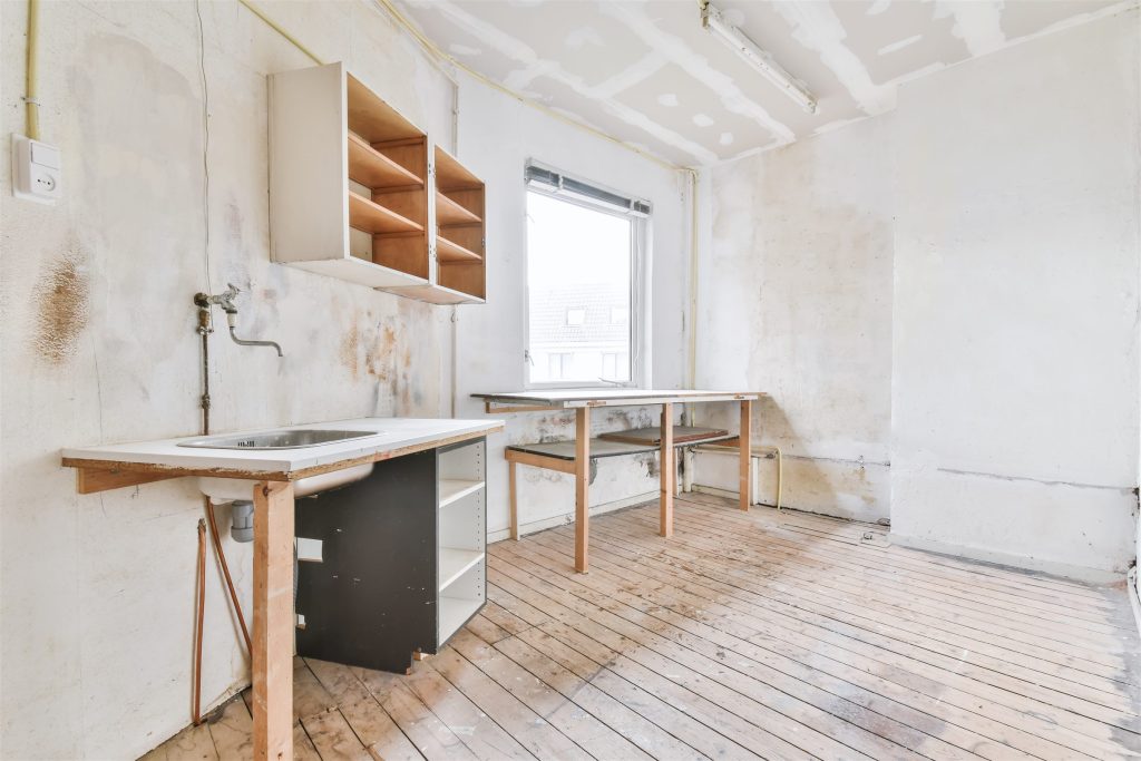 Gutted kitchen after demolition with exposed plumbing and bare walls