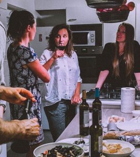 Friends gathered around a kitchen island with food and wine during a dinner party