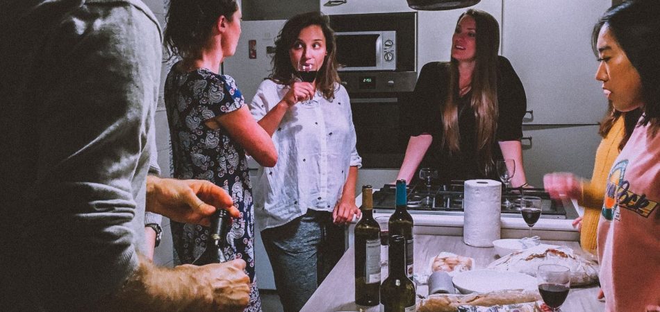 Friends gathered around a kitchen island with food and wine during a dinner party