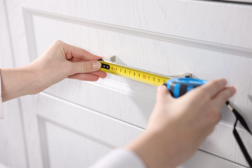 Tape measure held against a kitchen cabinet during a site visit
