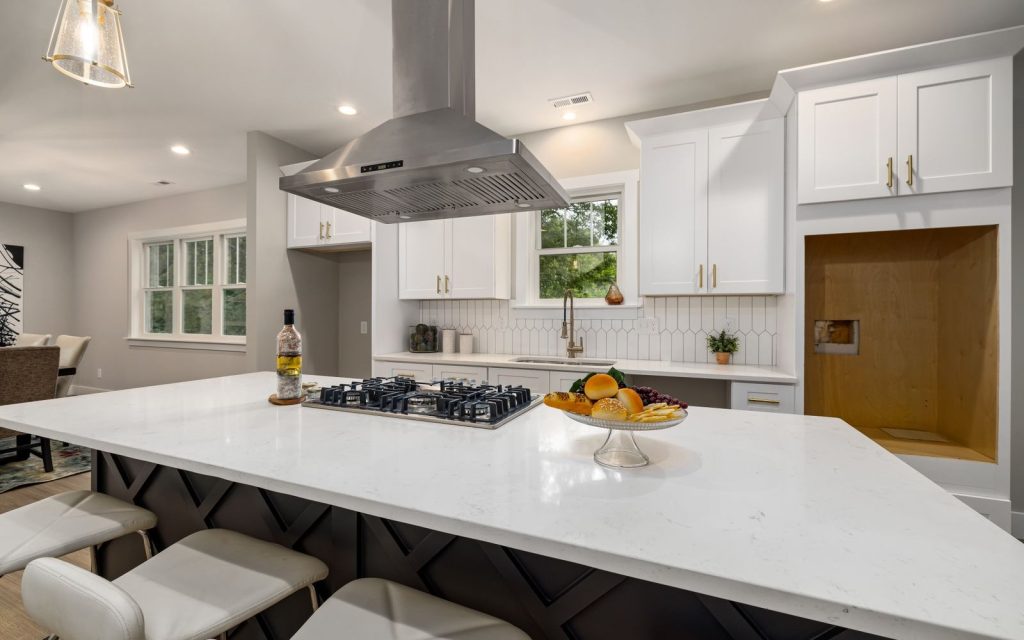 Stainless steel range hood over a gas cooktop in a white kitchen