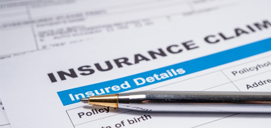 Insurance claim form for water damage on a desk with a pen