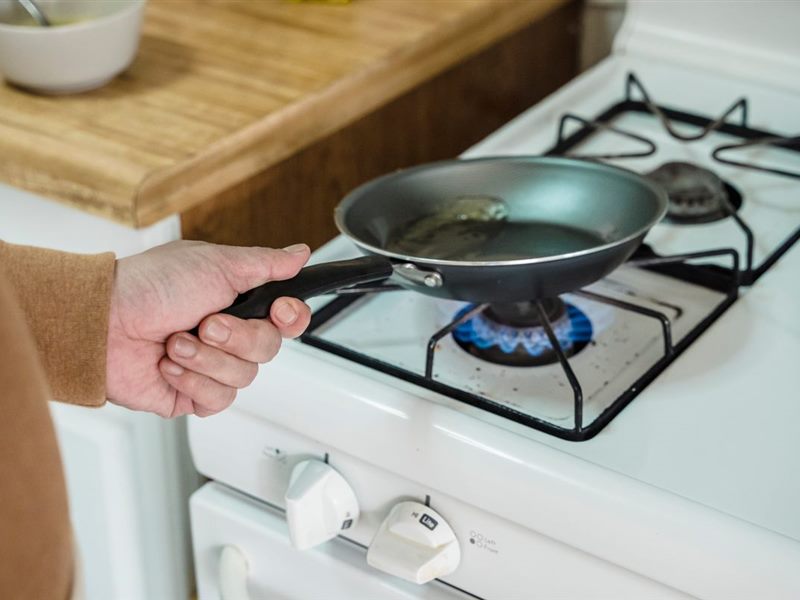 Pan held over an open gas burner flame on a kitchen range